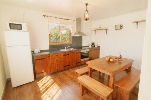 a kitchen with a wooden table and a white refrigerator at Vila Maria Quinta 13 " Maria Quinta" in Calheta