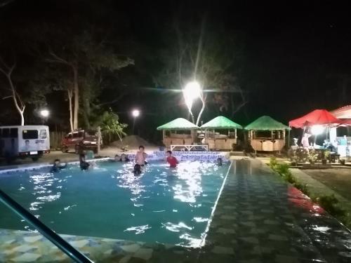 Bolinao的住宿－KNB WEST VILLA INN -PATAR，一群人在晚上在游泳池玩耍