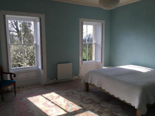 a bedroom with a bed and two windows at Swinton Manse & Gardens in Swinton