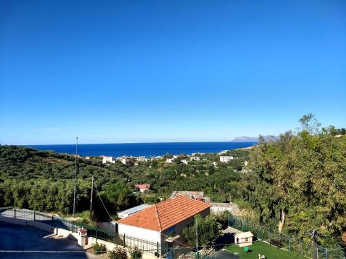 a view of a house with the ocean in the background at Modern 1-bedroom with BBQ & Roof Garden near Beach in Stalos