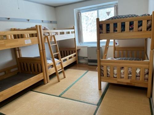a room with three bunk beds and a window at Kusatsu Kogen Youth Hostel in Kusatsu