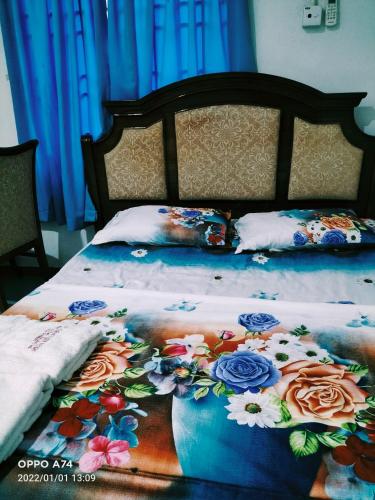 a bed with a floral comforter on it at Hotel Murah Pasir Puteh in Pasir Puteh