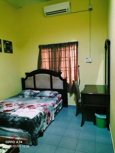 a bedroom with a bed and a table and a window at Hotel Murah Pasir Puteh in Pasir Puteh
