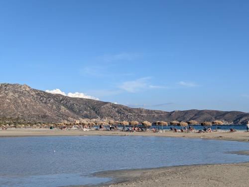 a beach with umbrellas and people on the beach at Modern 1-bedroom with BBQ & Roof Garden near Beach in Stalos