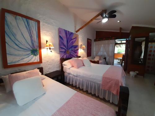 a bedroom with two beds and a painting on the wall at Villa Luzandi in Quimbaya