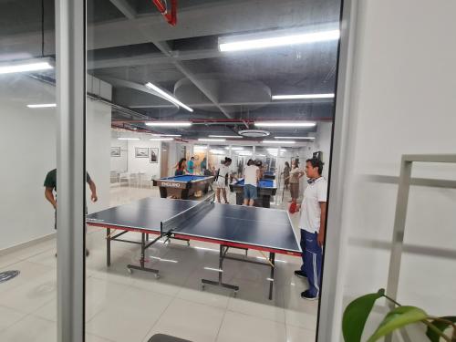 people standing around a ping pong table in a room at Confortable apartamento en conjunto Puerto Azul Club House in Ricaurte