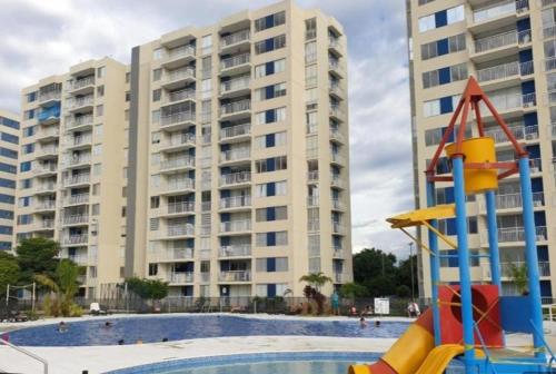 a large apartment building with a playground in front of a pool at Confortable apartamento en conjunto Puerto Azul Club House in Ricaurte