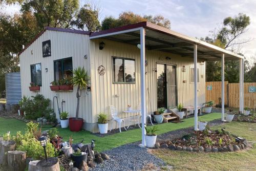 a white shed with a porch and some plants at Winganah Cottage in Murdunna