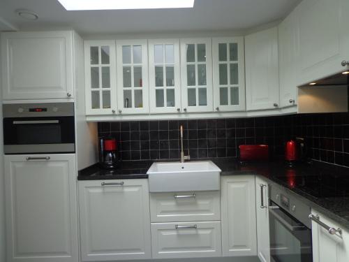 a white kitchen with white cabinets and a sink at B&B Domaine du Vieux Chêne in Stoumont