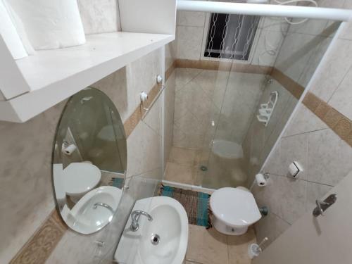y baño con aseo blanco y espejo. en Chalé da Ana - Ilhabela, en Ilhabela