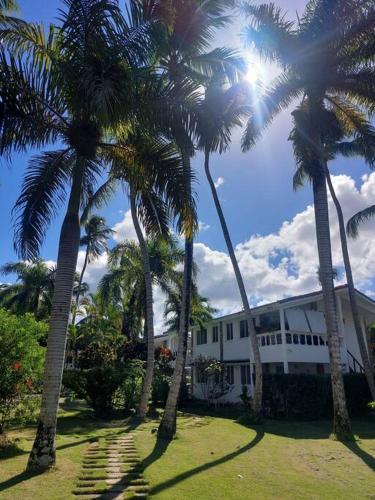 a group of palm trees in front of a building at Charming 1 bdr apt w/ pool 5min Popi beach in Las Terrenas