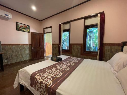 um quarto com uma cama e duas janelas em James Bungalow em Gili Trawangan