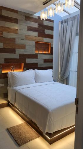 a bedroom with a white bed with a wooden wall at Yellow door Hua Hin in Hua Hin