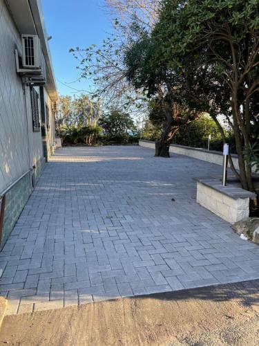 a brick driveway next to a building with a tree at House on the Sea in Mascali