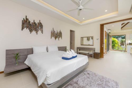 a bedroom with a large white bed and a chandelier at Laem Ka Residence by Tropiclook in Rawai Beach