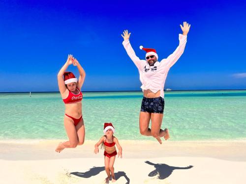 a group of people jumping in the air on a beach at Manta Stay Thoddoo, Maldives in Thoddoo