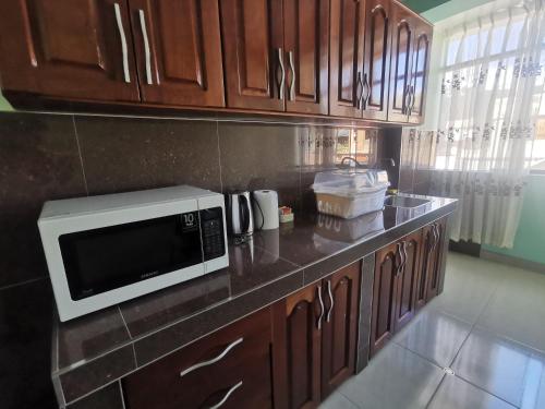 una cocina con armarios de madera y microondas en una encimera en Apartamento Hogareño con 3 dormitorios en Huancayo