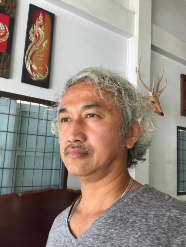 a man with a moustache sitting on a couch at EZ House in Sukhothai