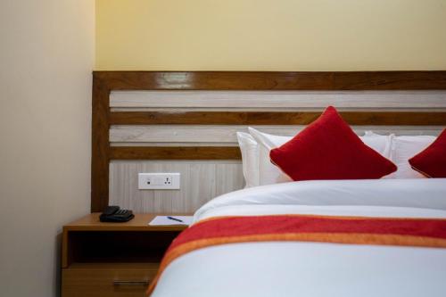 a bedroom with a large bed with red pillows at Chitwan Midtown Hotel in Bharatpur