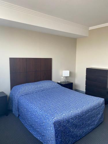 Schlafzimmer mit einem großen Bett mit blauer Decke in der Unterkunft The Bexley Motel in Sydney