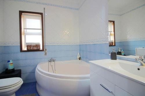 a bathroom with a white tub and a toilet and a sink at Casa com piscina para 10 pessoas - 5 min da praia Esposende in Esposende