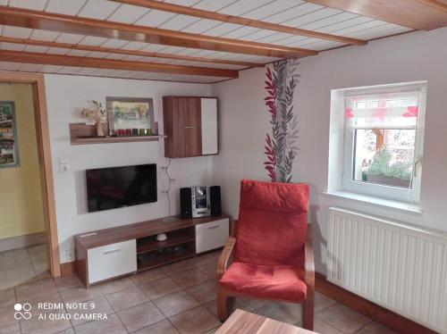 クロルト・ゴーリッシュにあるMichel's Ferienwohnungのリビングルーム(赤い椅子、テレビ付)