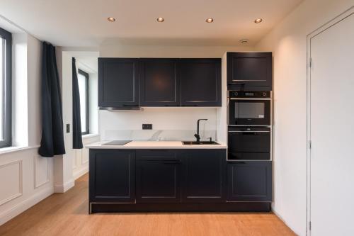 a kitchen with black cabinets and a sink at Studios Le Medicis vue Seine in Belbeuf