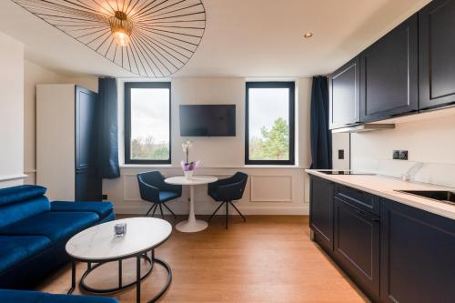 a kitchen and living room with a blue couch and a table at Studios Le Medicis vue Seine in Belbeuf
