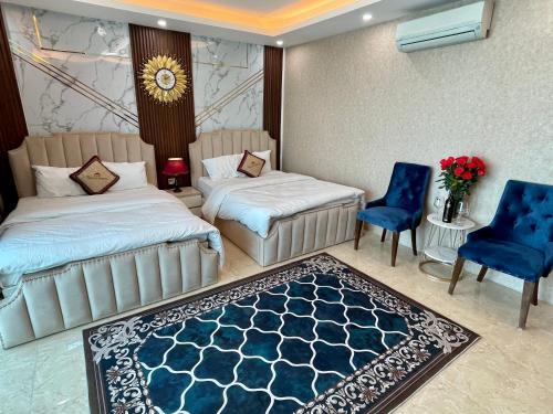 a bedroom with two beds and blue chairs and a rug at The Royal Hotel Near West Lake in Hanoi