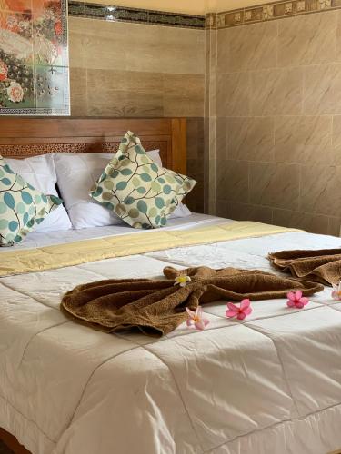 Una cama con una manta y flores rosas. en Tude's Family Homestay, en Ubud