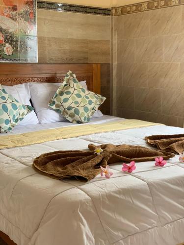 a bed with a blanket and pink flowers on it at Tude's Family Homestay in Ubud