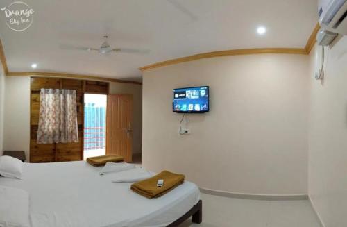a room with two beds and a tv on the wall at ORANGE SKY INN HOLIDAY HOME in Canacona