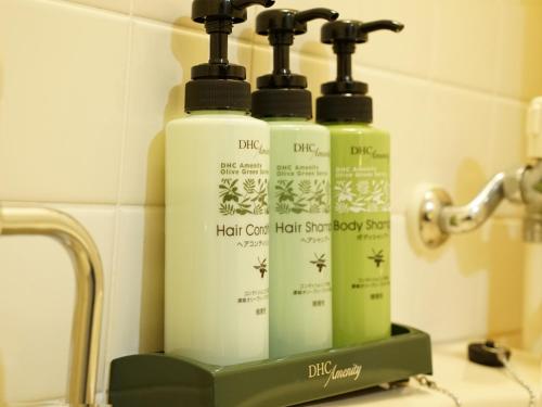 three bottles of hair care products sitting on a bathroom counter at Hotel AreaOne Takamatsu City in Takamatsu