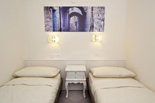 two beds in a room with a table and a painting at Achuza Bamarom in Safed