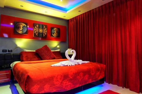 a bedroom with red curtains and a bed with a swan on it at Best 2 bedroom Apartment 2min walk to Patong Beach in Patong Beach