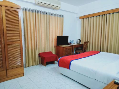 a bedroom with a bed and a desk with a computer at Hotel The Enchanted in Dhaka