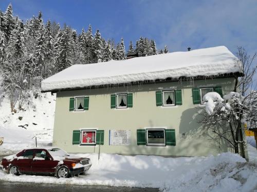 a snow covered house with a car parked in front of it at Ferienwohnung Saunahaus in Annaberg im Lammertal
