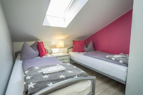 two beds in a small room with pink walls at Frau Holle in Westerland (Sylt)