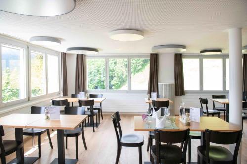 un comedor con mesas, sillas y ventanas en Hotel Tödiblick, en Braunwald