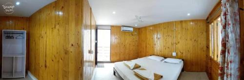 a bedroom with wooden walls and a bed in a room at ORANGE SKY INN HOLIDAY HOME in Canacona