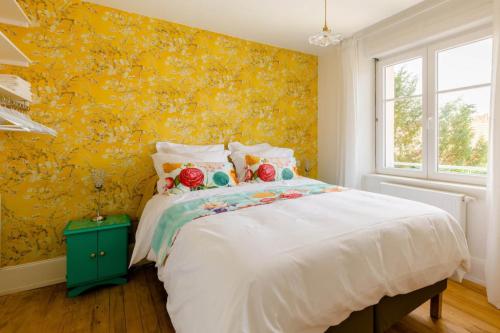 a bedroom with a bed and a yellow wall at Maison 1934 - Colmar Gare & Parking gratuit in Colmar