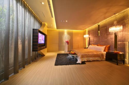a bedroom with a bed and a flat screen tv at Han Guan Motel in Taichung