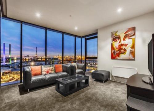 a living room with a couch and large windows at Lovely waterfront condo with swimming pool and gym in the heart of Docklands in Melbourne