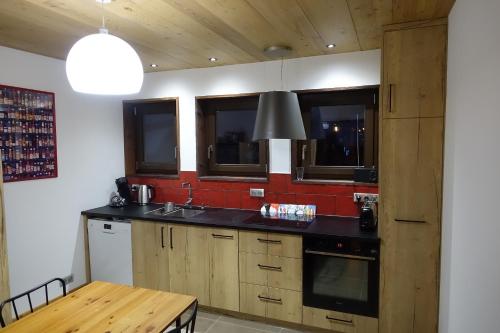 a kitchen with wooden cabinets and a table with a lamp at Appartement ensoleillé in Morzine