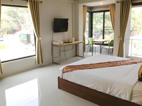 um quarto com uma cama, uma televisão e uma mesa em City Ratsada Apartment em Lampang