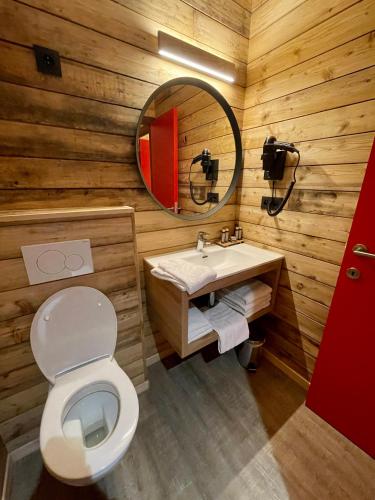 a wooden bathroom with a toilet and a mirror at The Bauhaus in Jurbise