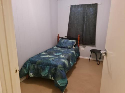 a bedroom with a bed with a blue comforter and a window at City Centre Apartments in Coober Pedy