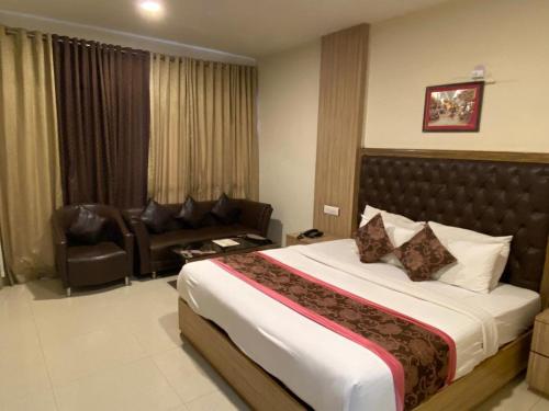 a bedroom with a large bed and a couch at Rama Trident, Katra in Katra