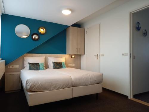 um quarto com uma cama com uma parede em tons de azul em Zeevonk Studio's & Appartementen em Katwijk aan Zee
