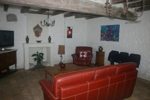 a living room with a red couch and a tv at L'Ancienne Cave in Prinçay